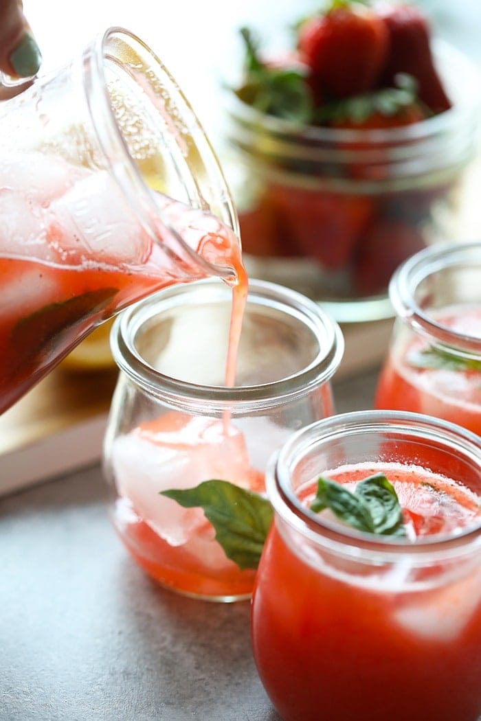 strawberry basil lemonade being poured into a glass