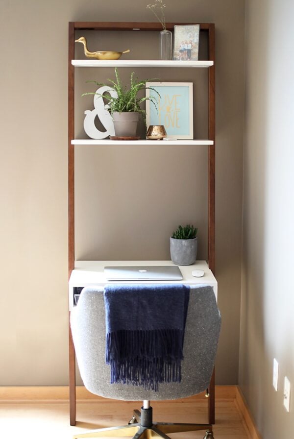 a ladder desk and chair in a room with a shelf.