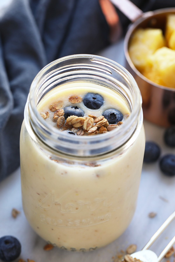 a jar of oatmeal with blueberries and granola transformed into a Ginger Pineapple Smoothie.