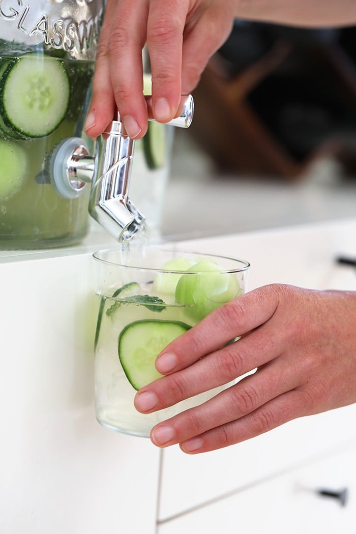 cucumber vodka drink dispensed in glass with cucumber slices
