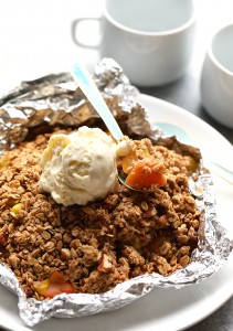 peach crumble in foil with spoon.