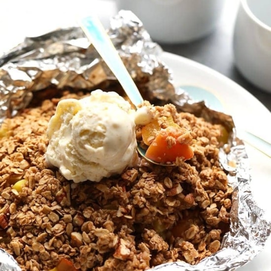 peach crumble in foil with spoon.