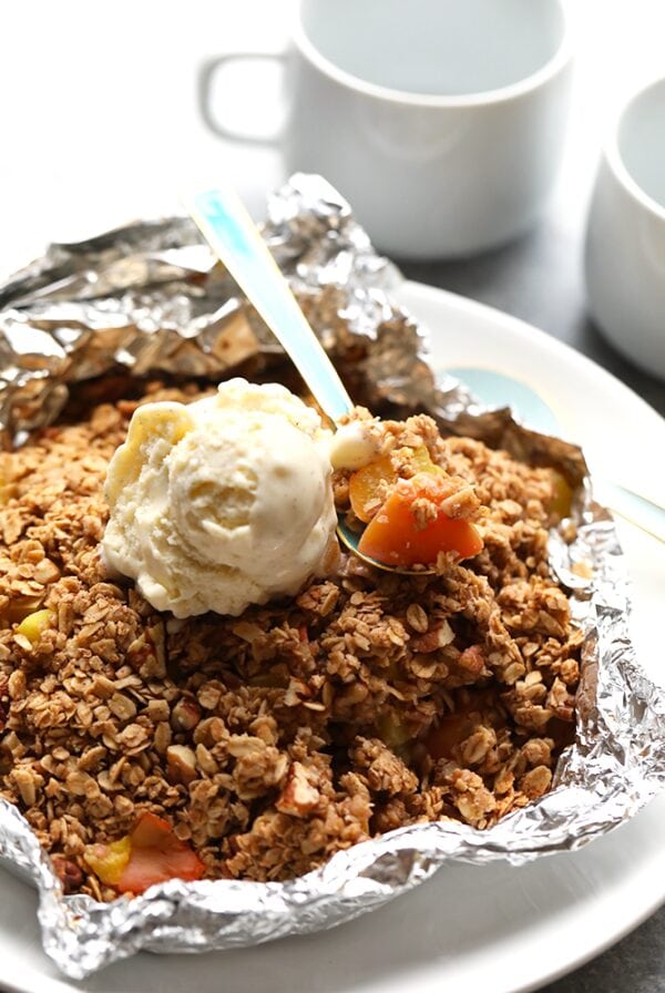 peach crumble in foil with spoon.