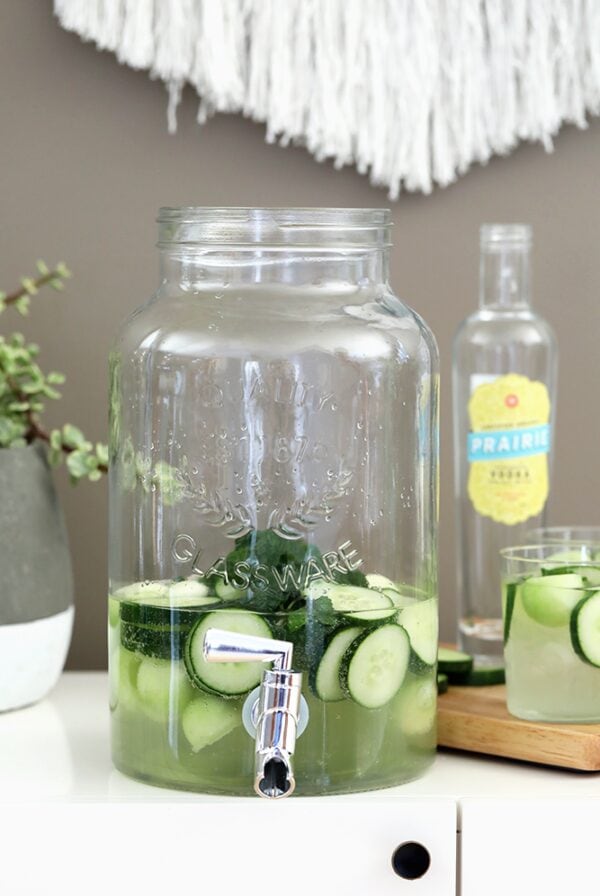 A glass jug with cucumber-infused water and a glass of cucumber vodka.