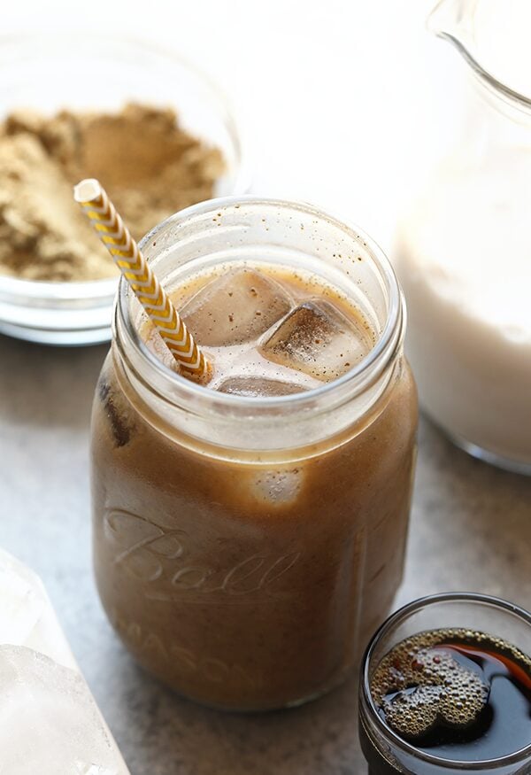 a jar of iced coffee with a straw next to it.