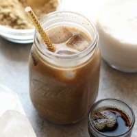 a protein drink in a mason jar filled with cold brew coffee and a straw.