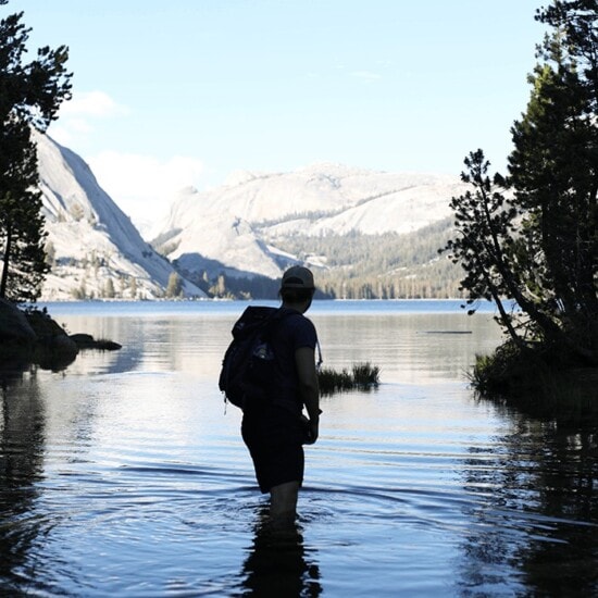 A person exploring Yosemite National Park by wading through a body of water.