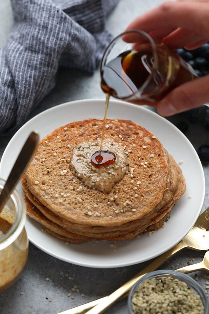 stack of pancakes with almond butter and maple syrup