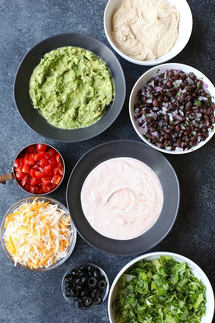 healthy taco dip ingredients in bowls ready to be mixed