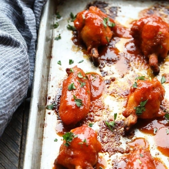 BBQ chicken wings being baked on a sheet.
