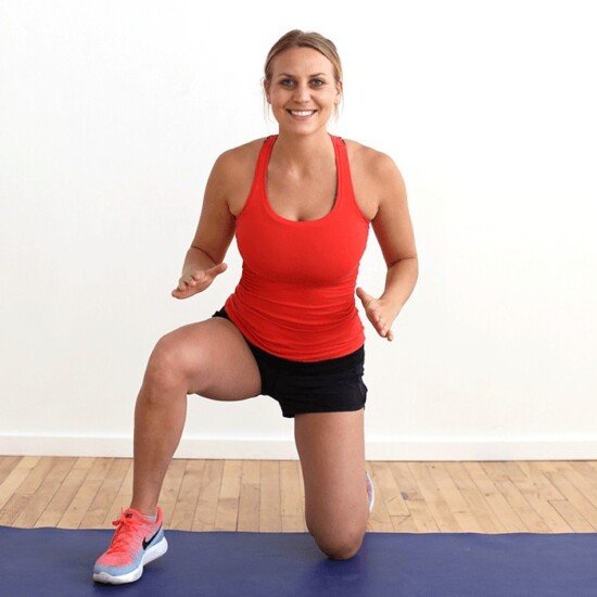 A woman performing a squat exercise on a blue mat as part of her cardio and strength workout.