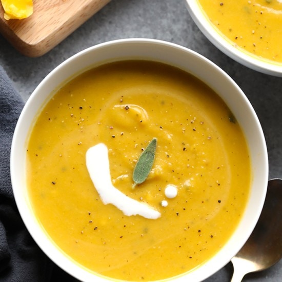 Two bowls of butternut squash soup with sour cream.