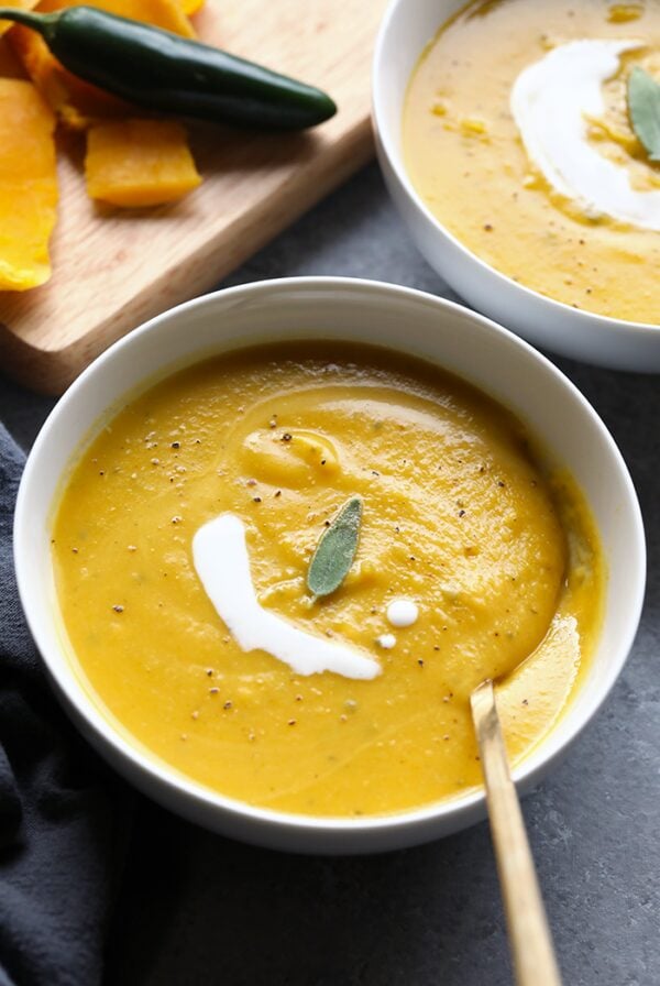 Two bowls of Butternut Squash soup with sour cream and sage.