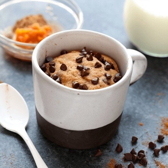 a healthy pumpkin mug cake filled with chocolate chips and a spoon.