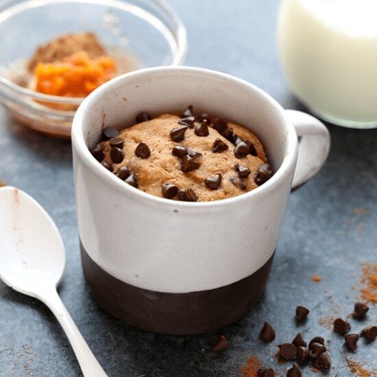 a healthy pumpkin mug cake filled with chocolate chips and a spoon.