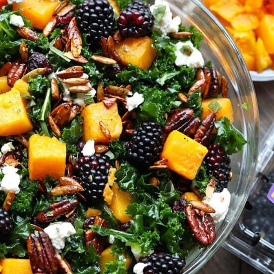A Butternut Squash Kale Salad topped with blackberries and pecans.