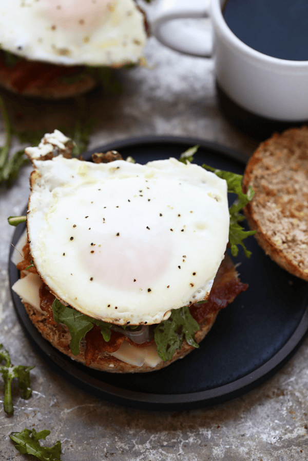 A breakfast sandwich with an egg and a cup of coffee.