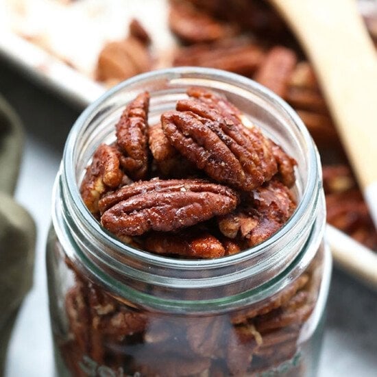 Roasted pecans in a jar on a table.
