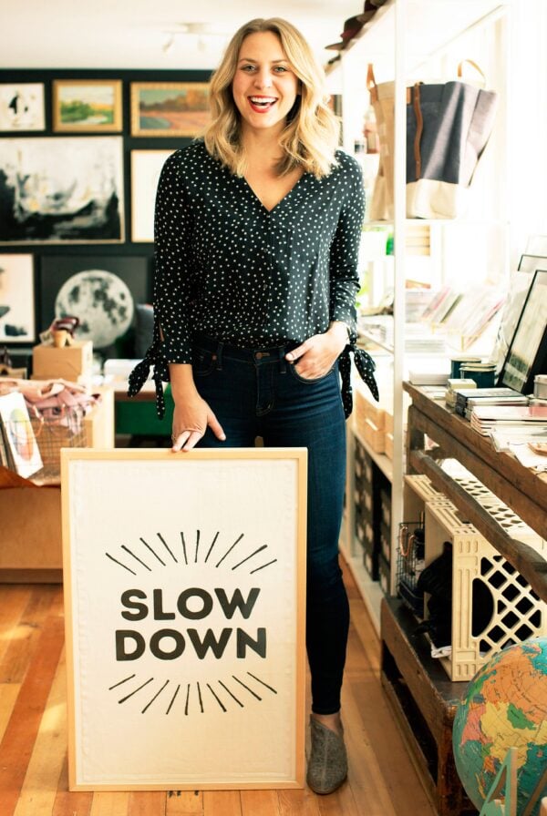 facing her fear of speed, a woman courageously stands in front of a sign that says slow down.