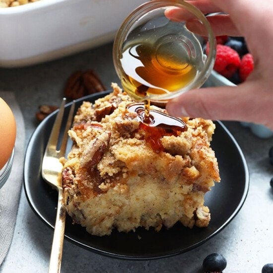 A person is drizzling honey on an Overnight French Toast Bake.