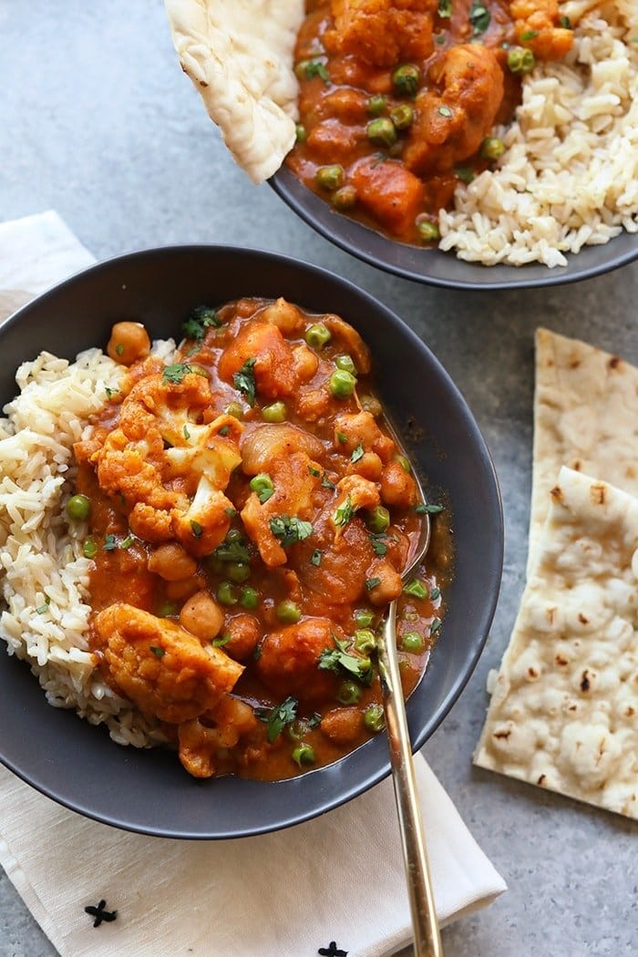 Pack your lunch or dinner with tons of veggies and warm spices. This Cauliflower Tikka Masala Recipe is vegetarian, loaded with hearty ingredients, and the best recipe for fall or winter meal prep! Tikka masala in a bowl with naan on the side
