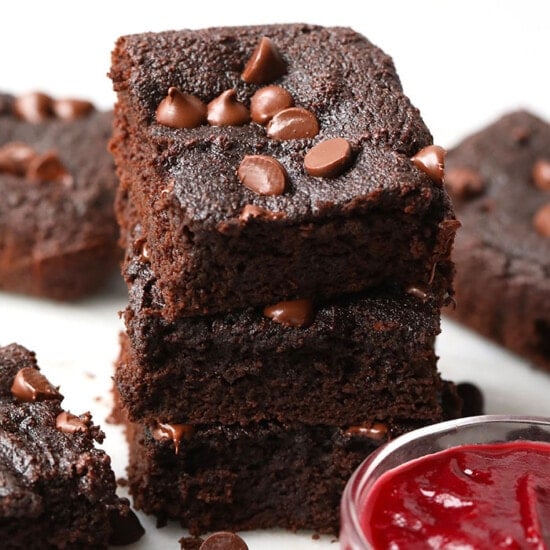 A stack of healthy brownies with raspberry sauce.