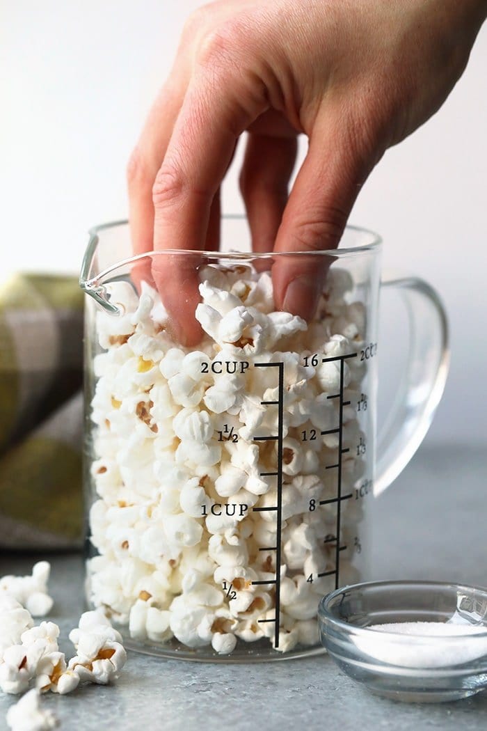 hand reaching for popcorn in glass