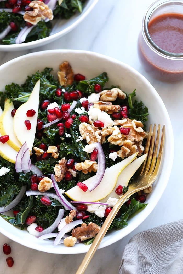 Make this kale pomegranate salad with fresh pears, walnuts, pomegranate arils, and the most delicious homemade pomegranate salad dressing! kale salad in bowl