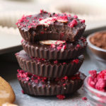 a stack of chocolate almond butter cups topped with raspberries and nuts.