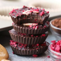 a stack of chocolate almond butter cups topped with raspberries and nuts.