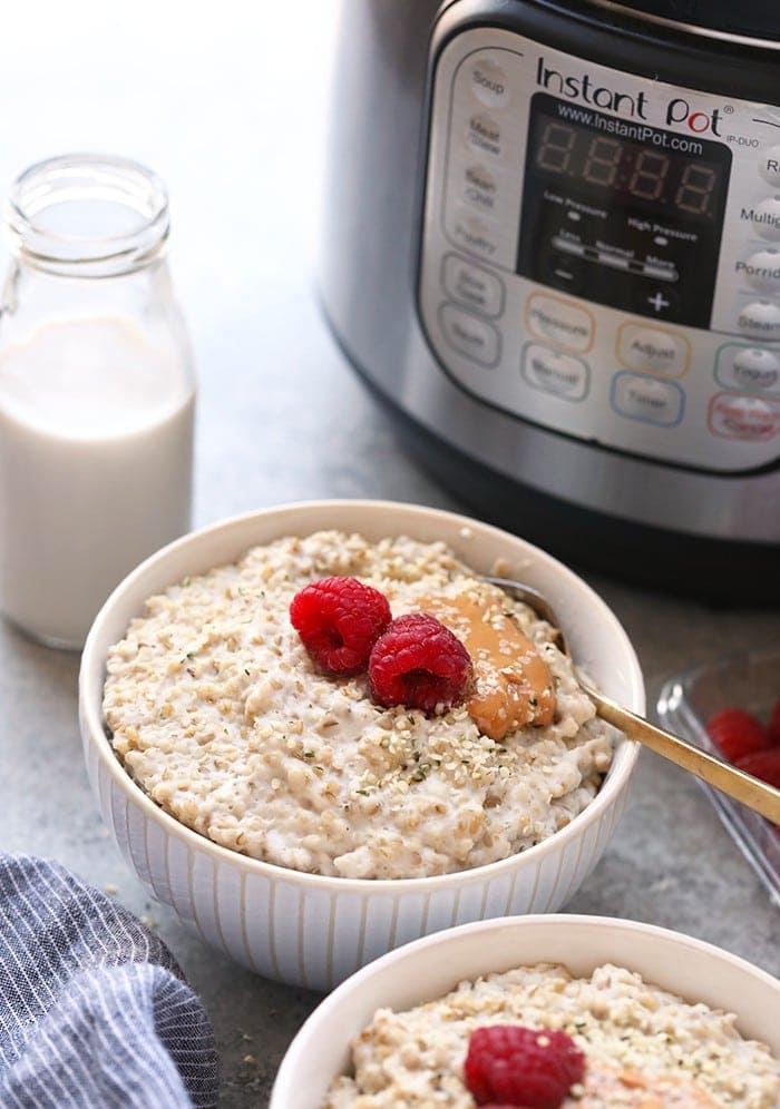 Instant Pot stålskuren havre i en skål bredvid Instant Pot.