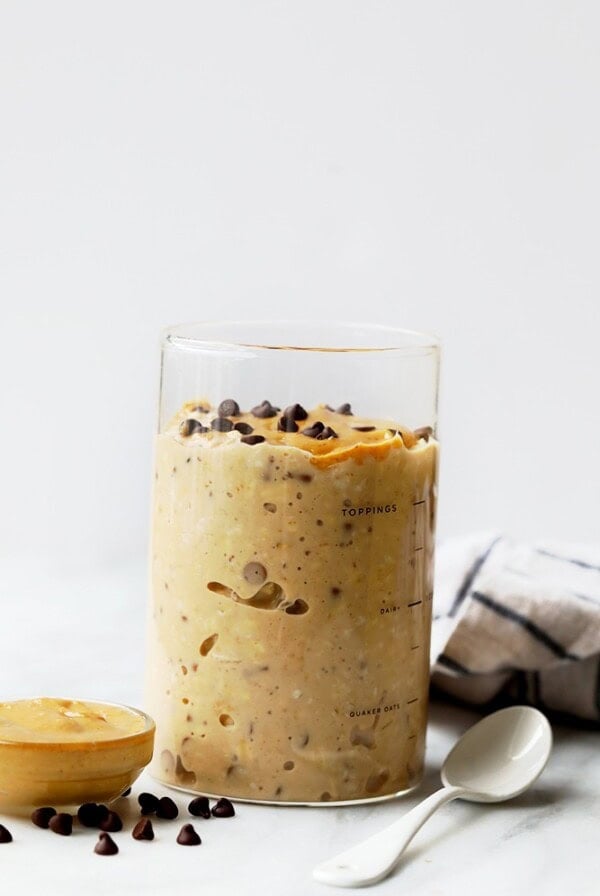a glass of overnight oats with peanut butter cookie dough and a spoon.