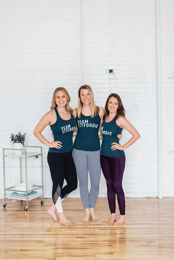 Three women play 21 questions while posing for a photo in a yoga studio.