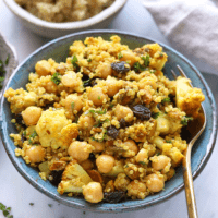a bowl of couscous with golden roasted cauliflower and chickpeas, garnished with raisins.