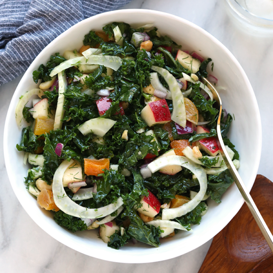 a bowl of kale salad with apples.