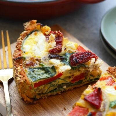 A slice of sweet potato crust quiche on a cutting board.