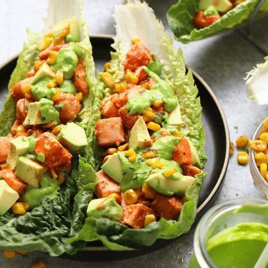 A plate of lettuce wraps with avocado and corn.