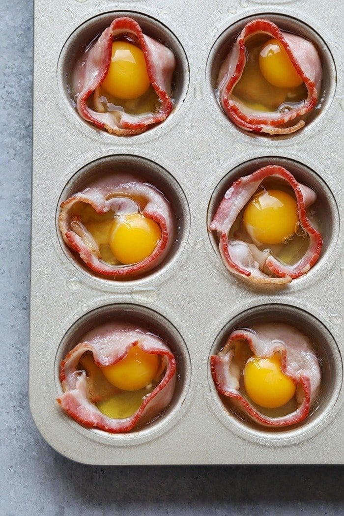 cracking raw eggs into the middle of bacon