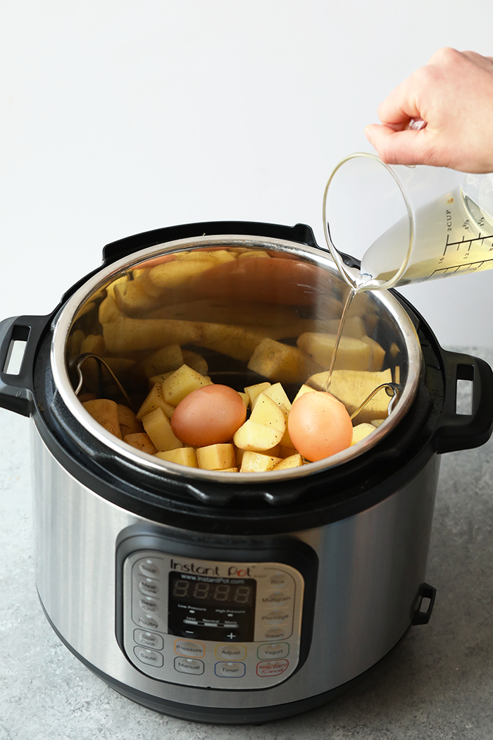 Pouring vinegar into the instant pot over potatoes.