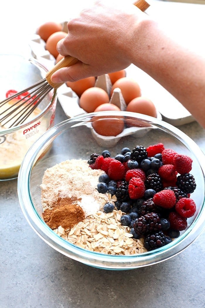 triple berry baked oatmeal cup ingredients being mixed in a bowl