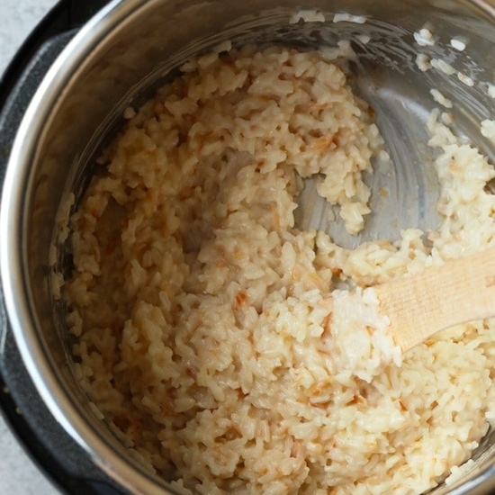 An instant pot filled with coconut rice and a wooden spoon.