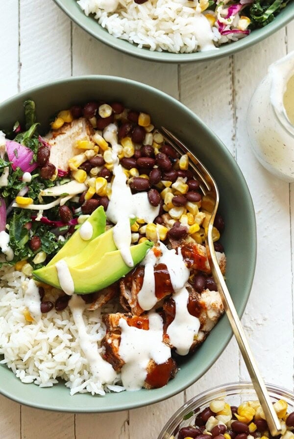 Two bowls with rice, beans, avocado, and BBQ chicken.