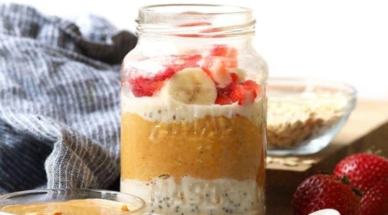 Overnight oats in a jar topped with peanut butter, strawberries and bananas.