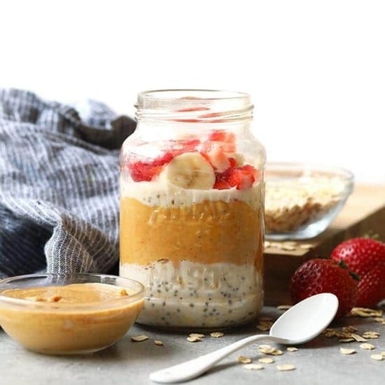 Overnight oats in a jar topped with peanut butter, strawberries and bananas.