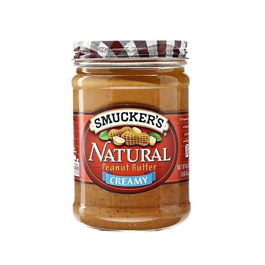 A jar of Smucker's natural peanut butter next to a bowl of banana baked oatmeal on a white background.