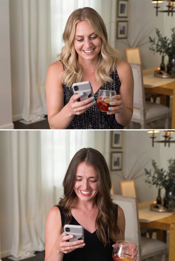 A woman is multitasking by holding both a cell phone and a glass of wine.