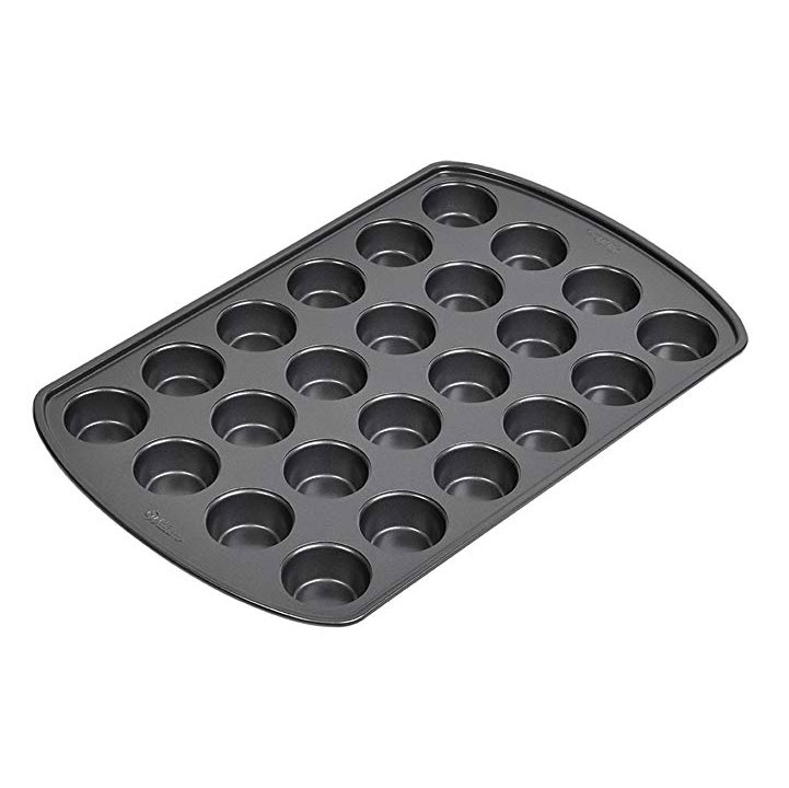 a black muffin pan with 12 holes perfect for making pumpkin peanut butter cups.