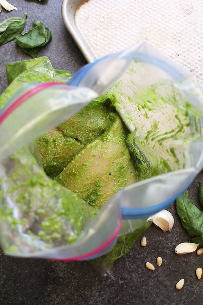 Chicken in pesto being mixed in a bag before cooking.