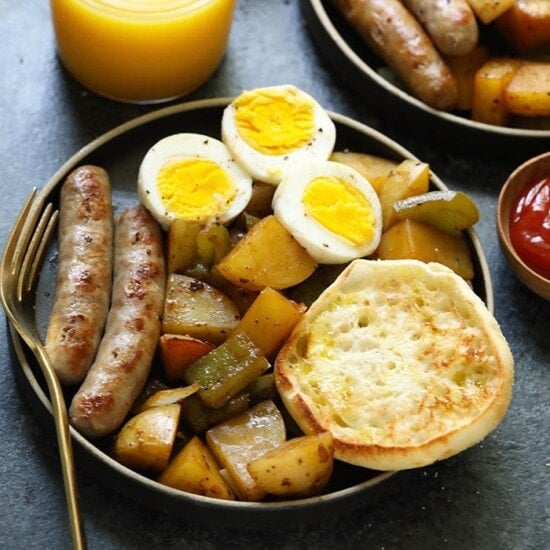 A plate with sausage, eggs, and potatoes.