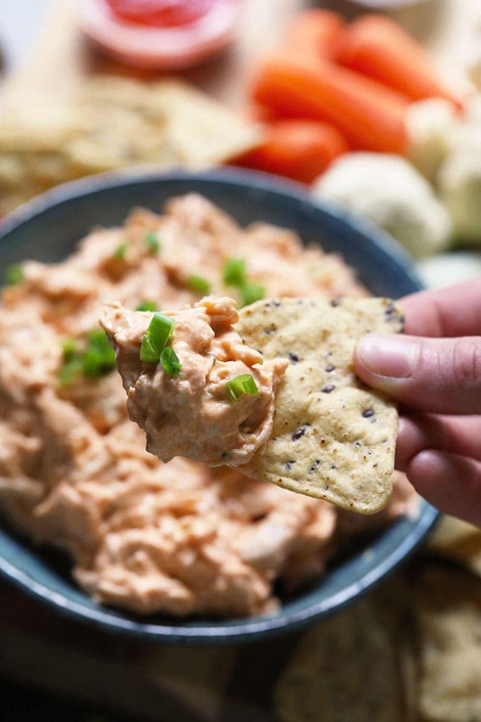 Hand holding a chip with buffalo chicken dip 
